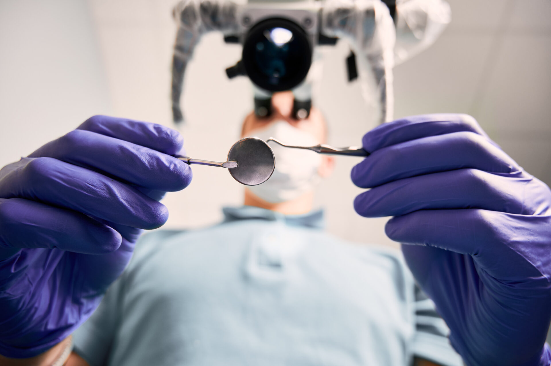 Male dentist holding dental mirror and explorer.
